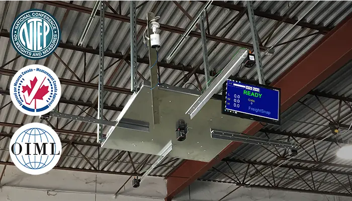 FreightSnap's FS 5000 pallet dimensioner hanging from a tall warehouse ceiling. NTEP, Measurement Canada, and OIML certification logos are also pictured.